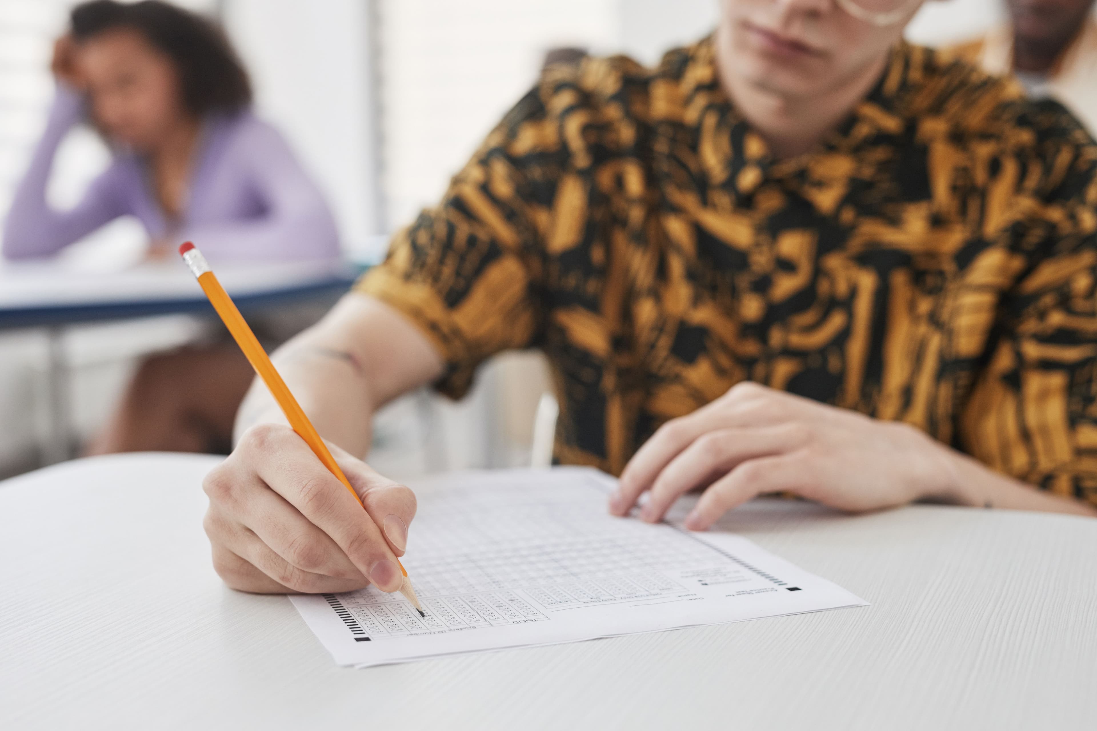 The image shows a student taking an exam, with the focus on the test paper.